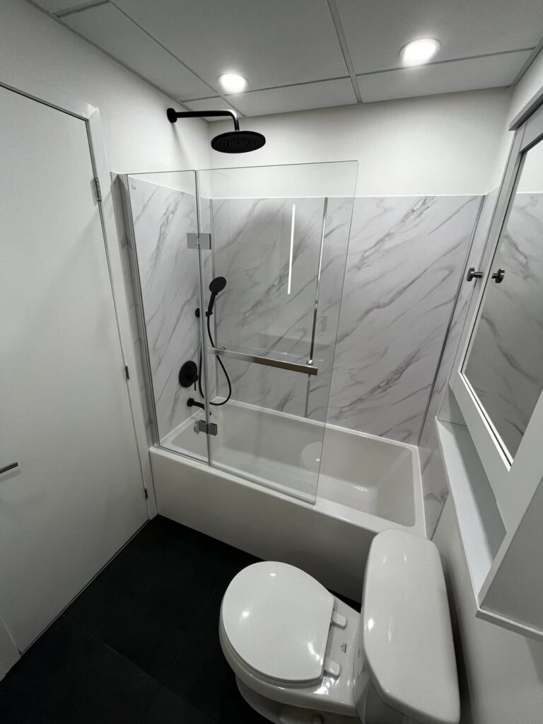 Baignoire-douche avec panneaux de marbre et porte vitrée
