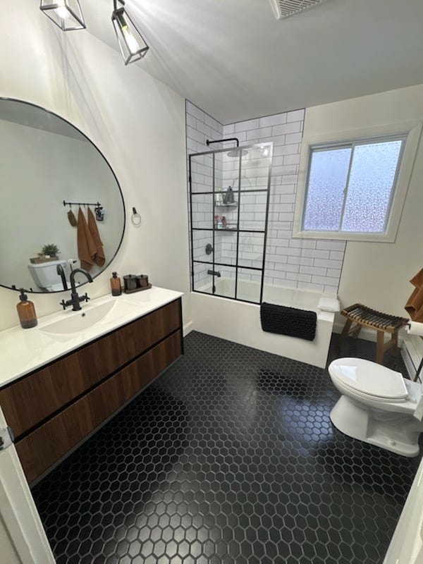 Salle de bain rénovée avec vanité de bois et plancher noir