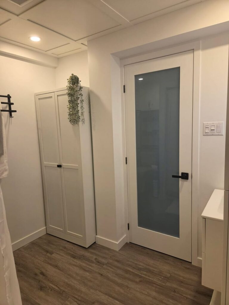 Rangement encastré et porte vitrée dans une salle de bain rénovée