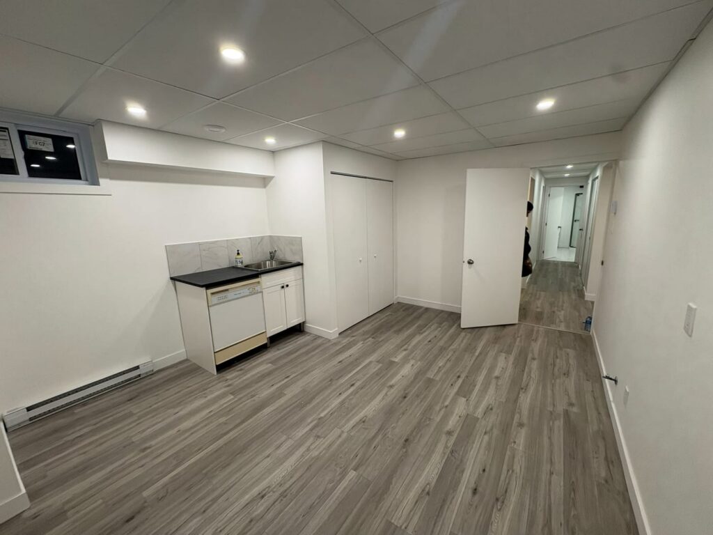 Sous-sol aménagé avec coin cuisine et plancher de vinyle